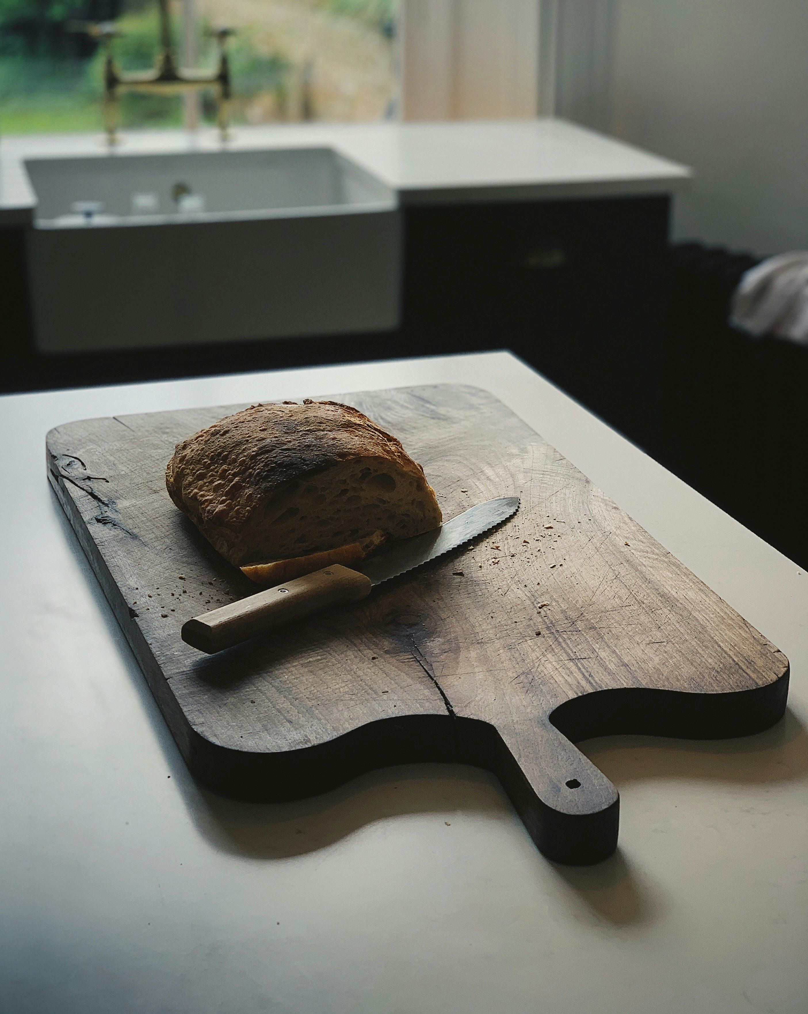 baked bread on chopping board with knife